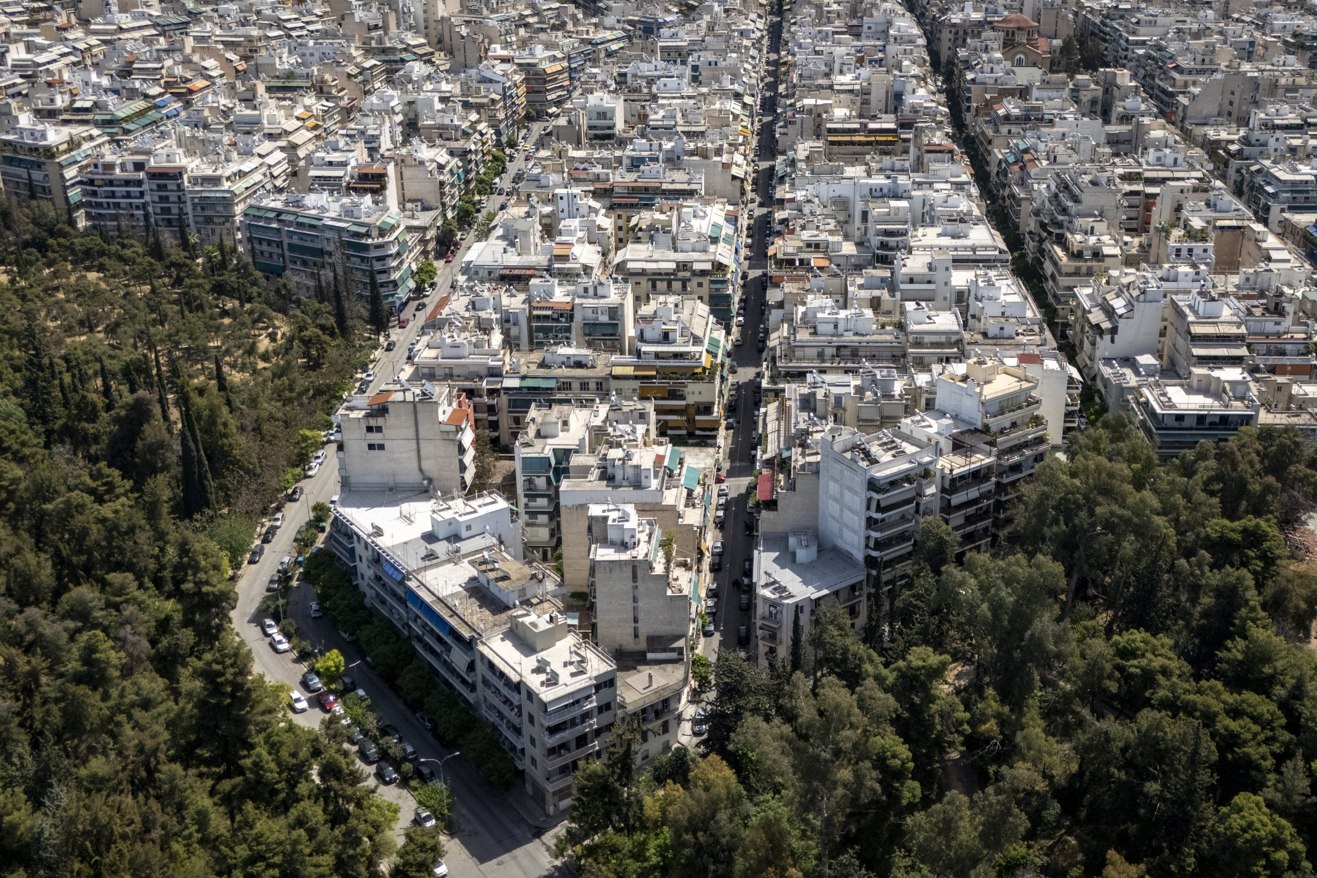 This photograph shows an aerial view of the city of Athens on April 18, 2025. On the hills of Kypseli, one of Athens' most densely populated neighborhoods, residents stroll through a small park recently created to bring a breath of fresh air when the Greek capital is sweltering, an initiative that residents and experts say is long overdue. Most of Athens' buildings and streets were built with materials more than 40 years old, which absorb heat in the summer. (Photo by Aris Messinis / AFP)