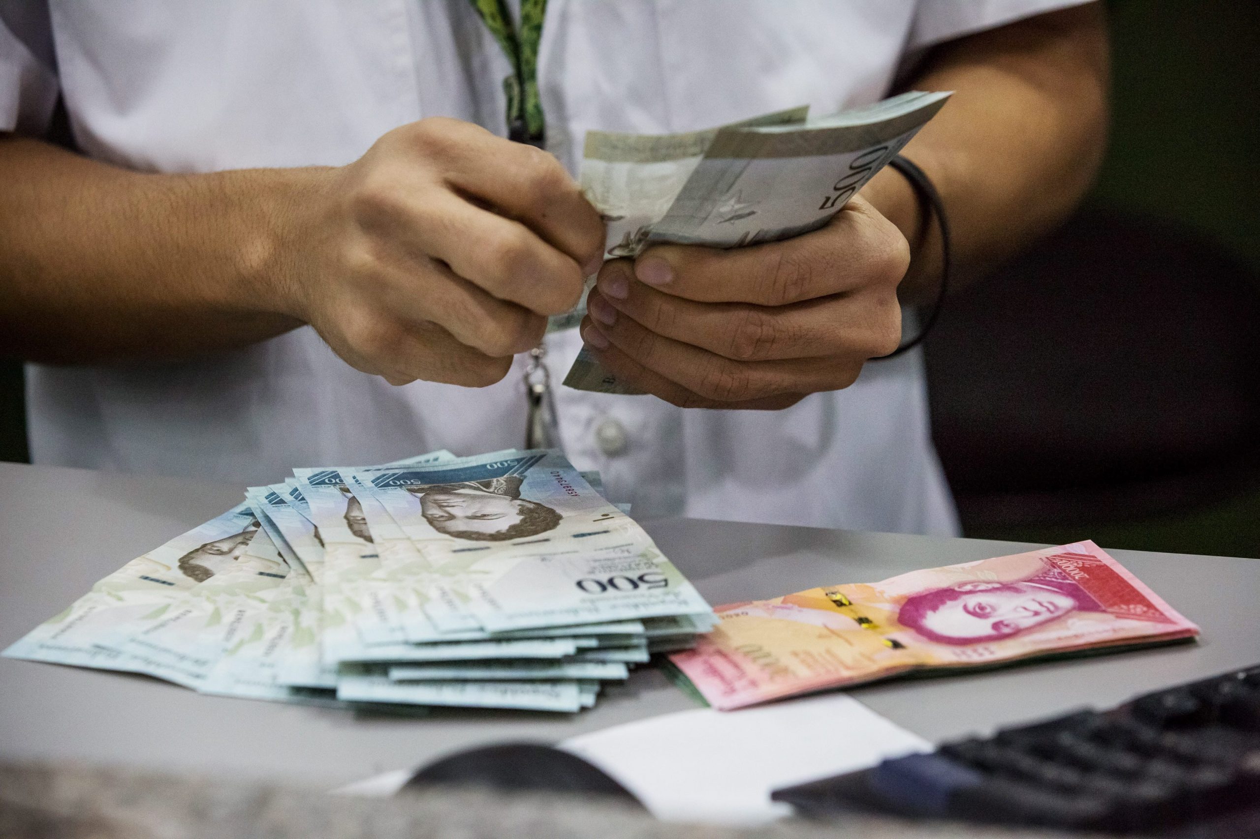 Venezuelanos distribuem notas de bolívares em troca de moedas em Bogotá